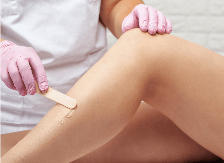 Leg waxing with pink gloves and spatula.