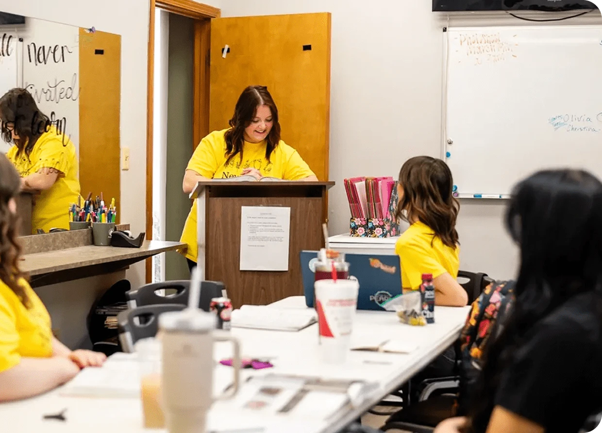 Woman speaking at a classroom podium meeting.