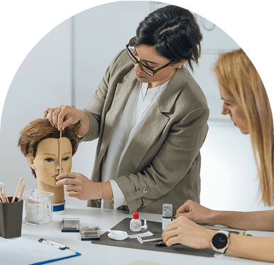 Makeup artists practicing on a mannequin head.