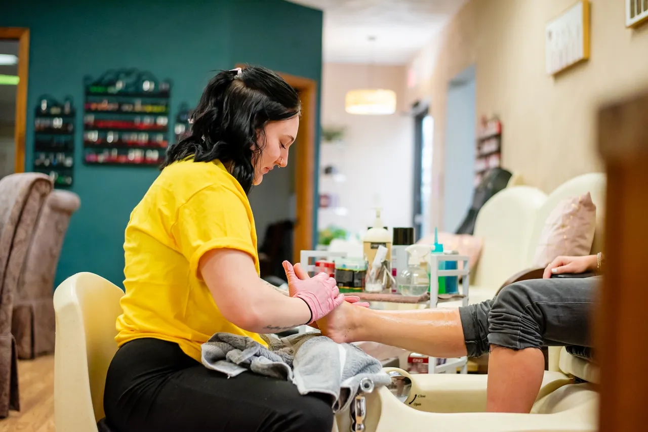 Person in yellow shirt doing a pedicure.