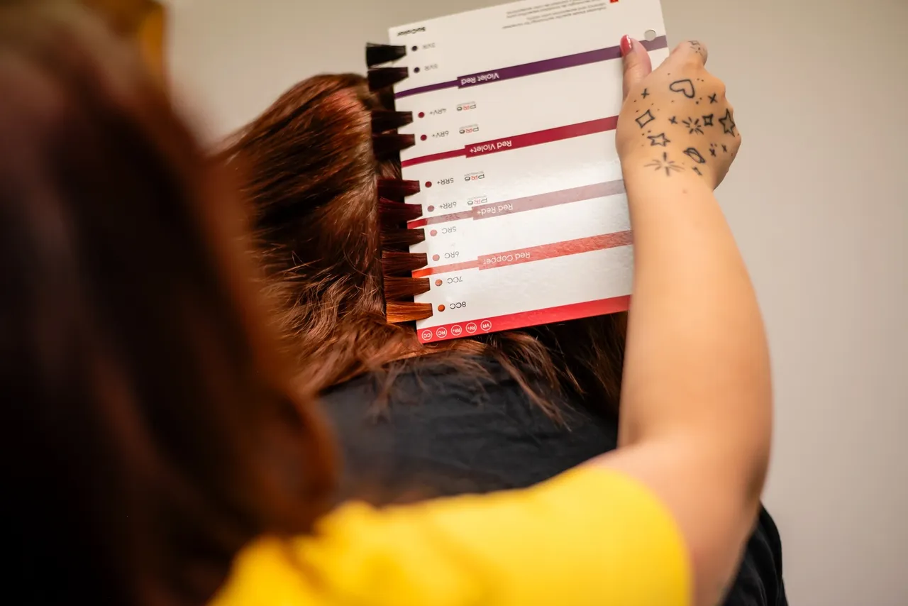 Hairdresser holds color swatches against hair